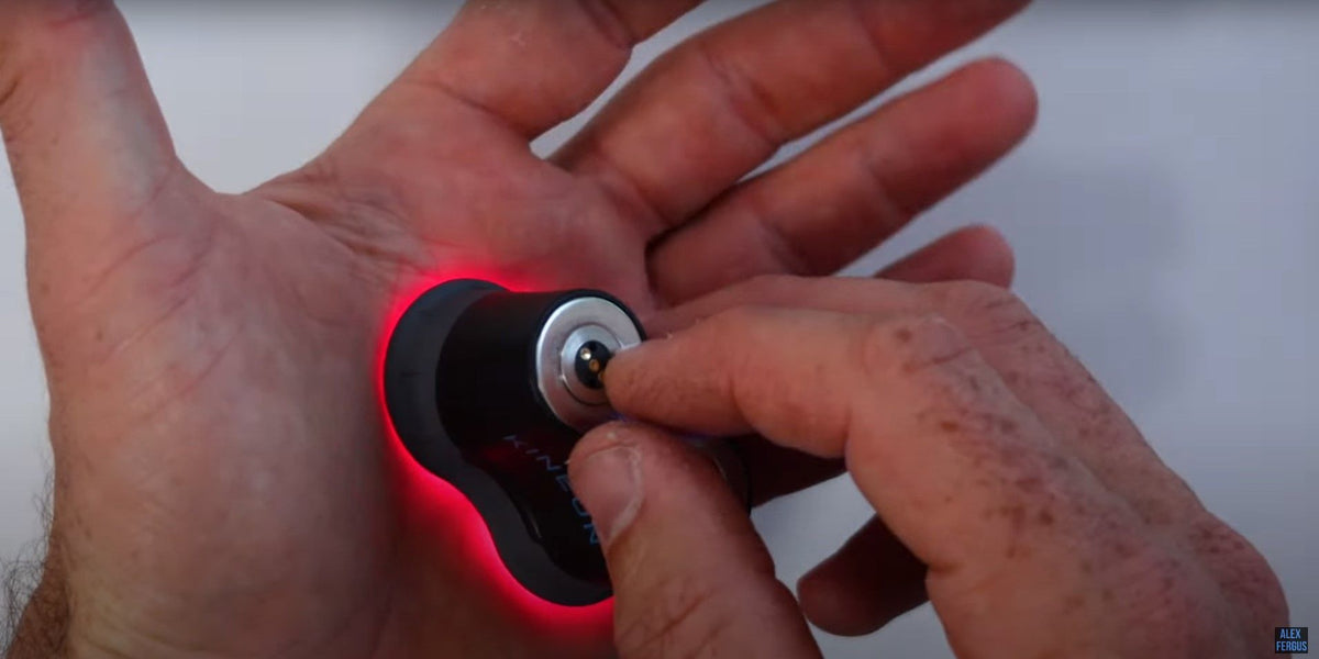A small targeted light device held against an open palm, with red light visible at the contact point.