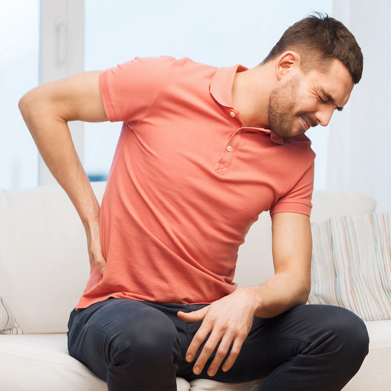 An adult placing a hand on his lower back