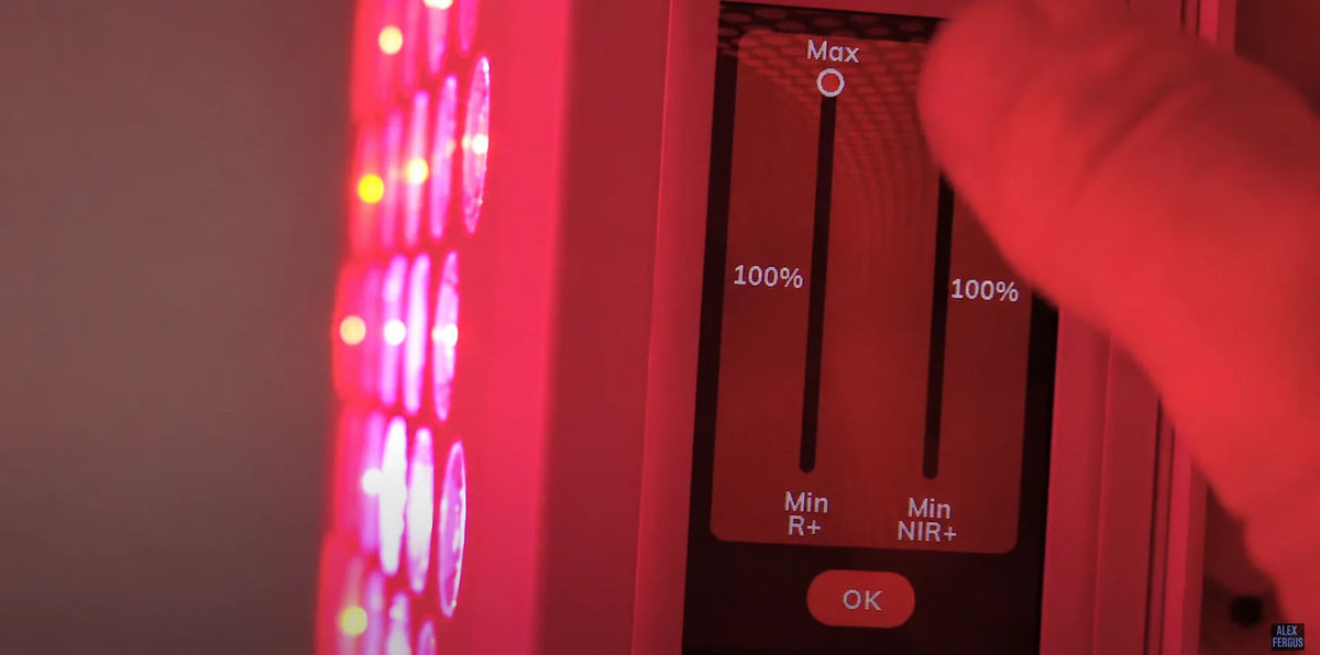 A hand adjusting the red and near-infrared controls of a light panel.