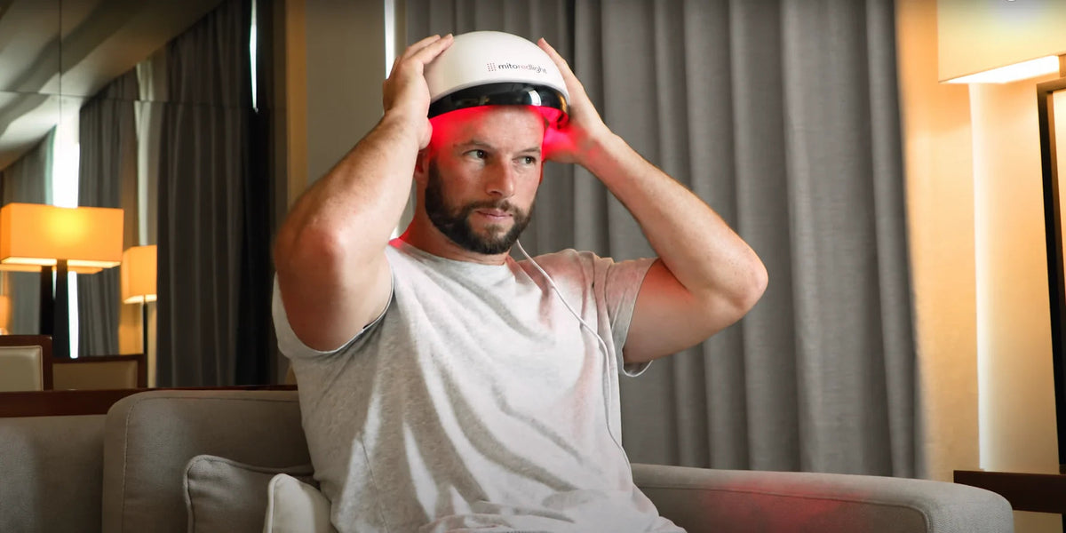An adult positioning a red-light hair helmet.
