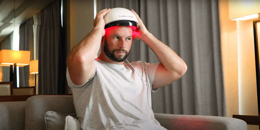 An adult positioning a red-light hair helmet.