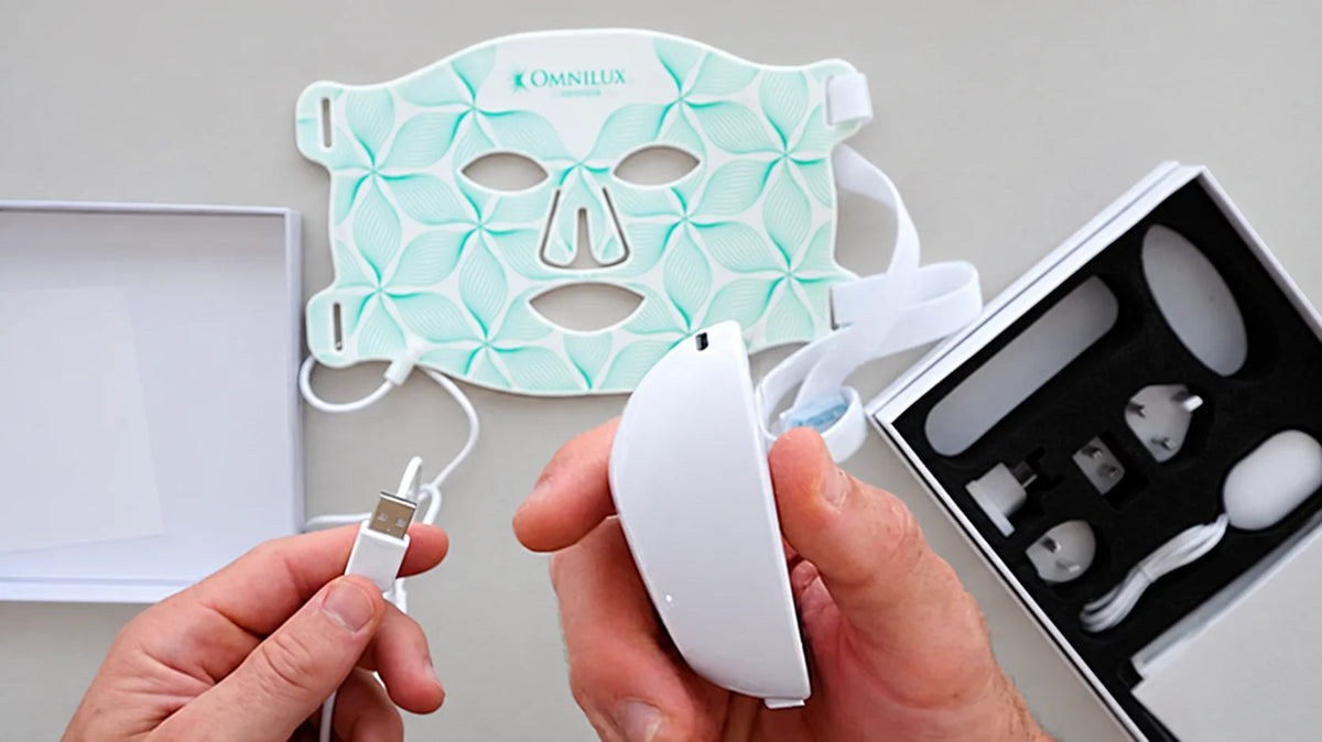 Hands connecting a controller beside a flexible LED face mask.