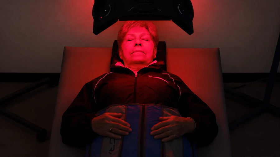 A reclining adult beneath a red light treatment device.