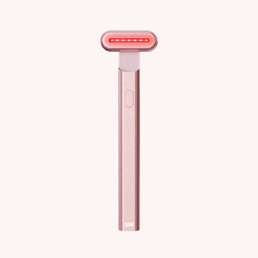 Rose-gold Solawave Radiant Renewal skincare wand with its red light head illuminated
