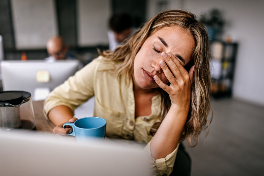 A woman resting her head on one hand beside a laptop